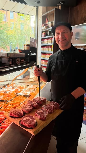 De slager lachend met een plank vol steaks